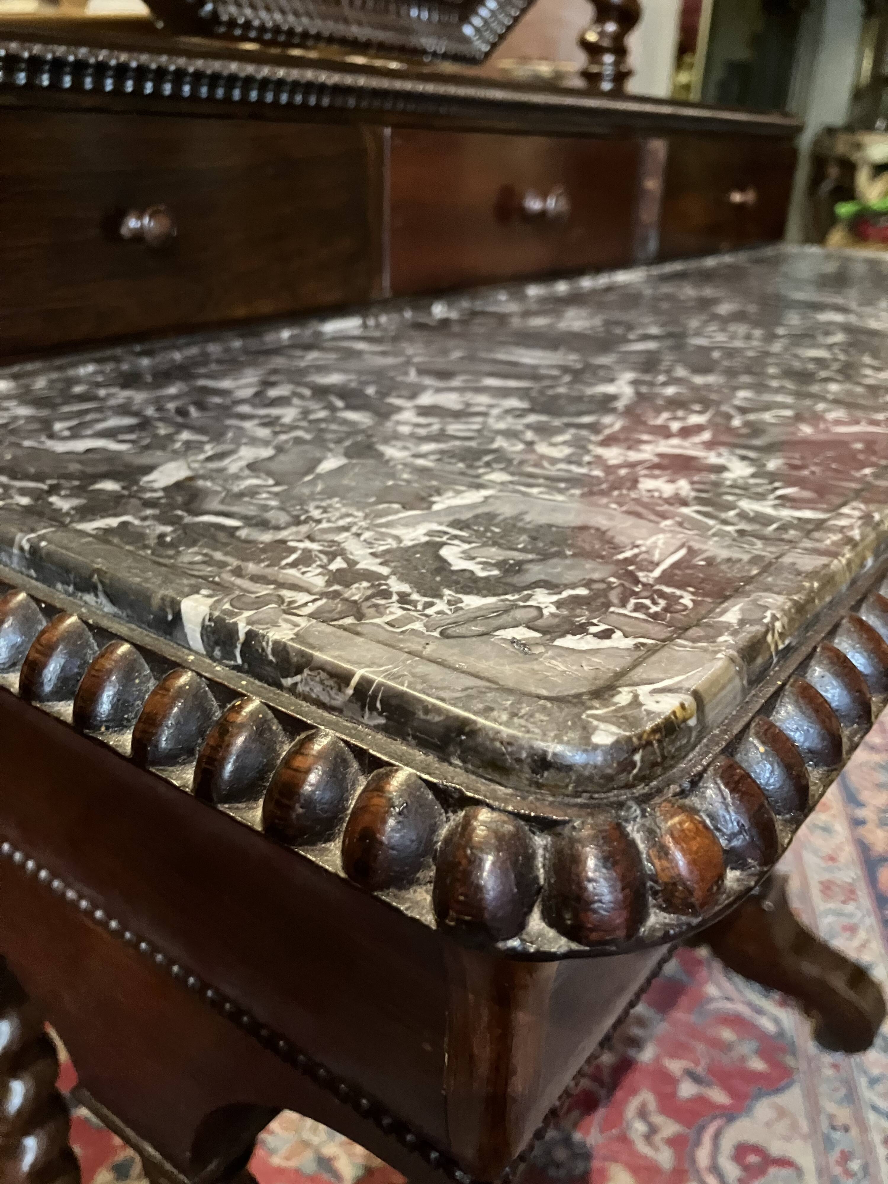 Antique English mahogany dressing table with carved details, black marble, and mirror.