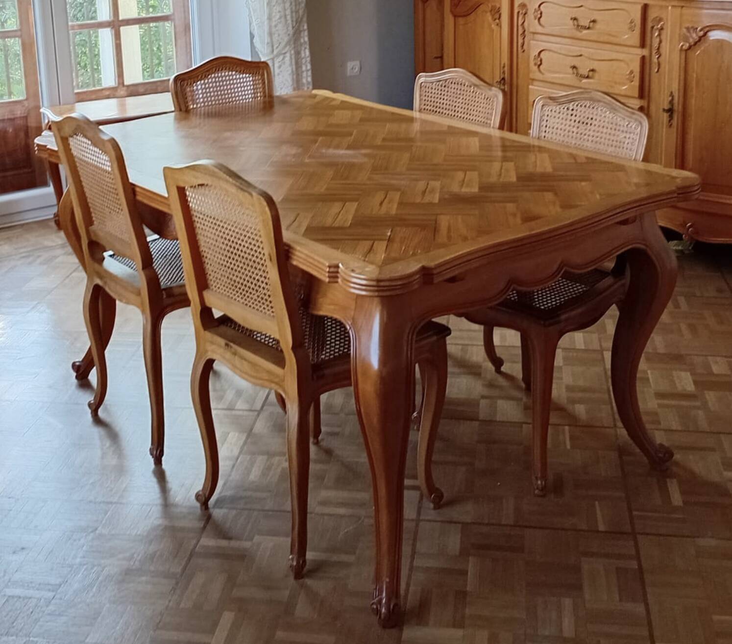 Carved wooden dining table and its 5 rattan caned chairs.