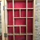Old hanging display case with 15 wooden boxes, red background + vintage glass door