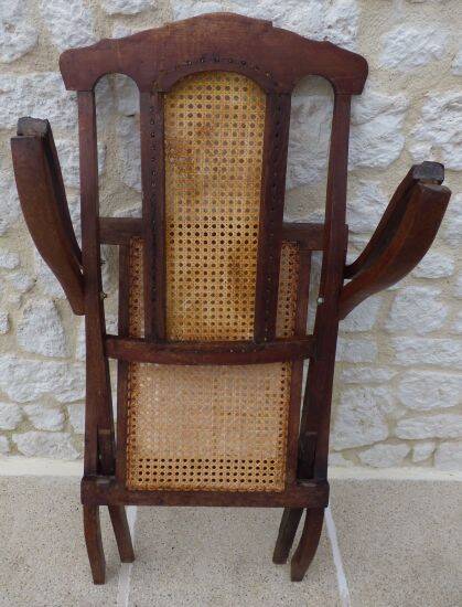 Antique folding chair with caned seat and backrest made of wood.