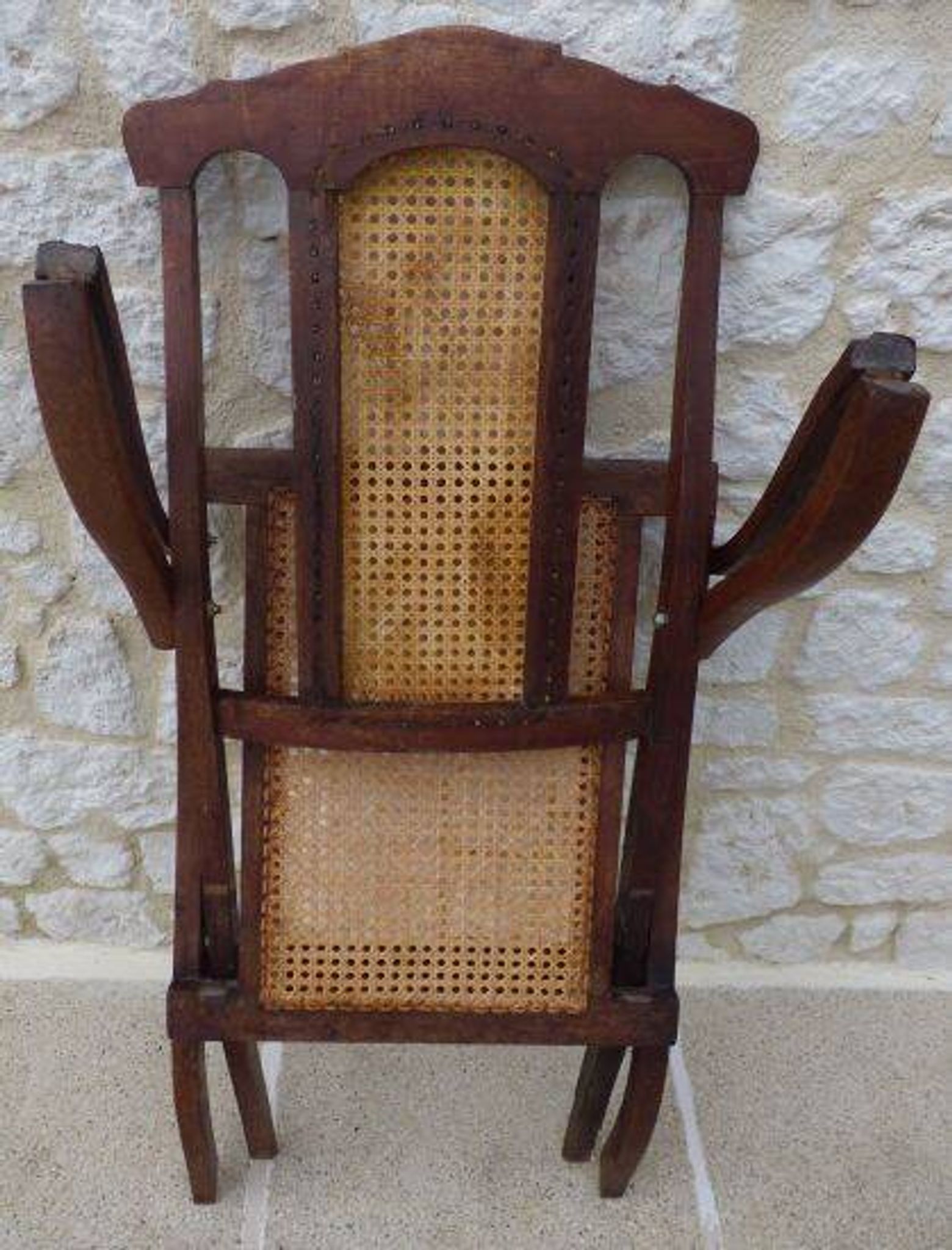 Antique folding chair with caned seat and backrest made of wood.