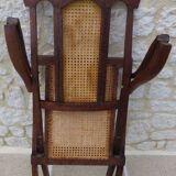 Antique folding chair with caned seat and backrest made of wood.