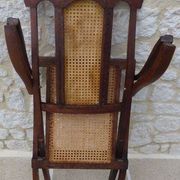 Antique folding chair with caned seat and backrest made of wood.