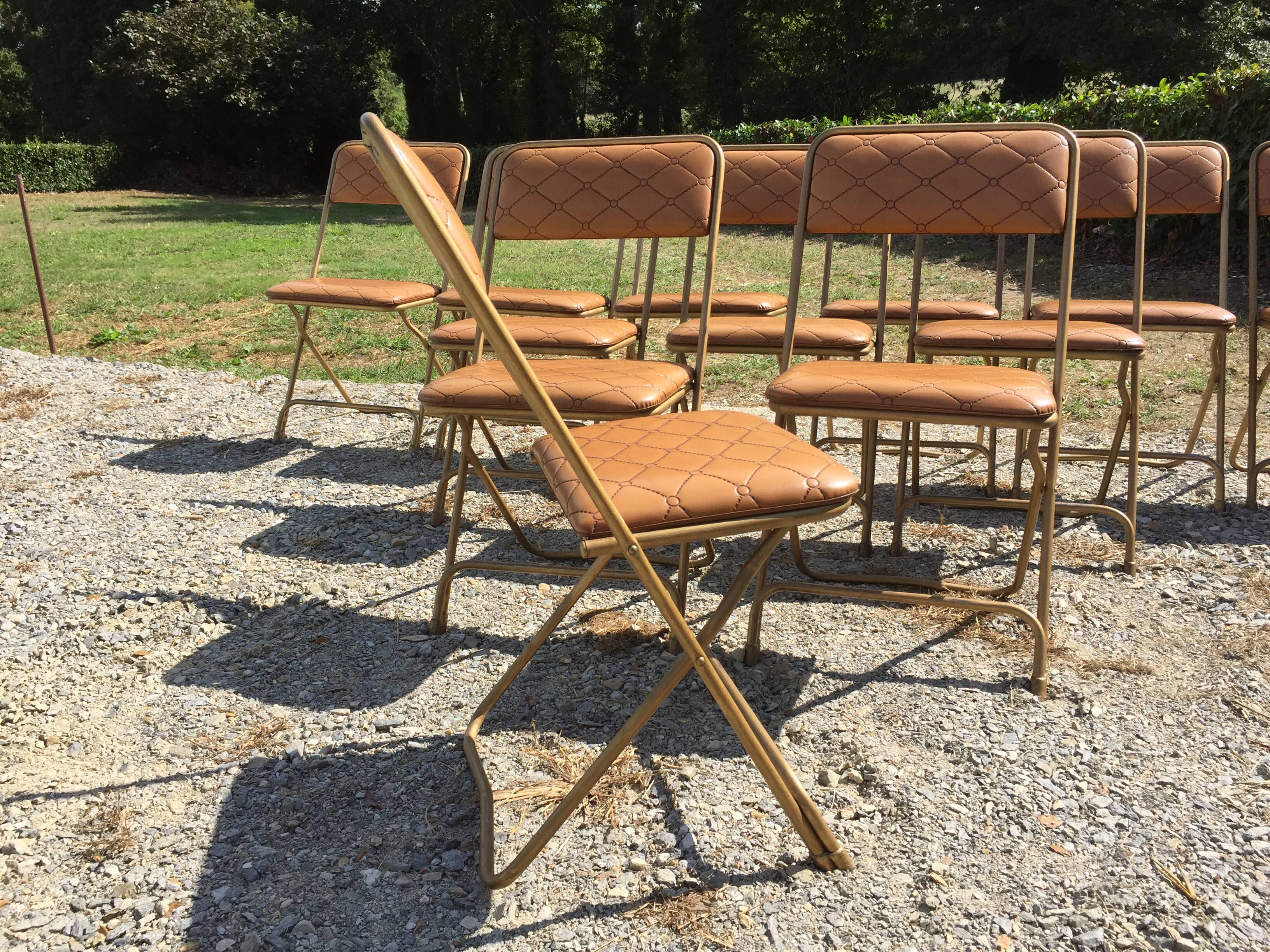 Set de 12 chaises vintage pliantes en skaï assises et dossiers matelassés à piètement tubulaire doré