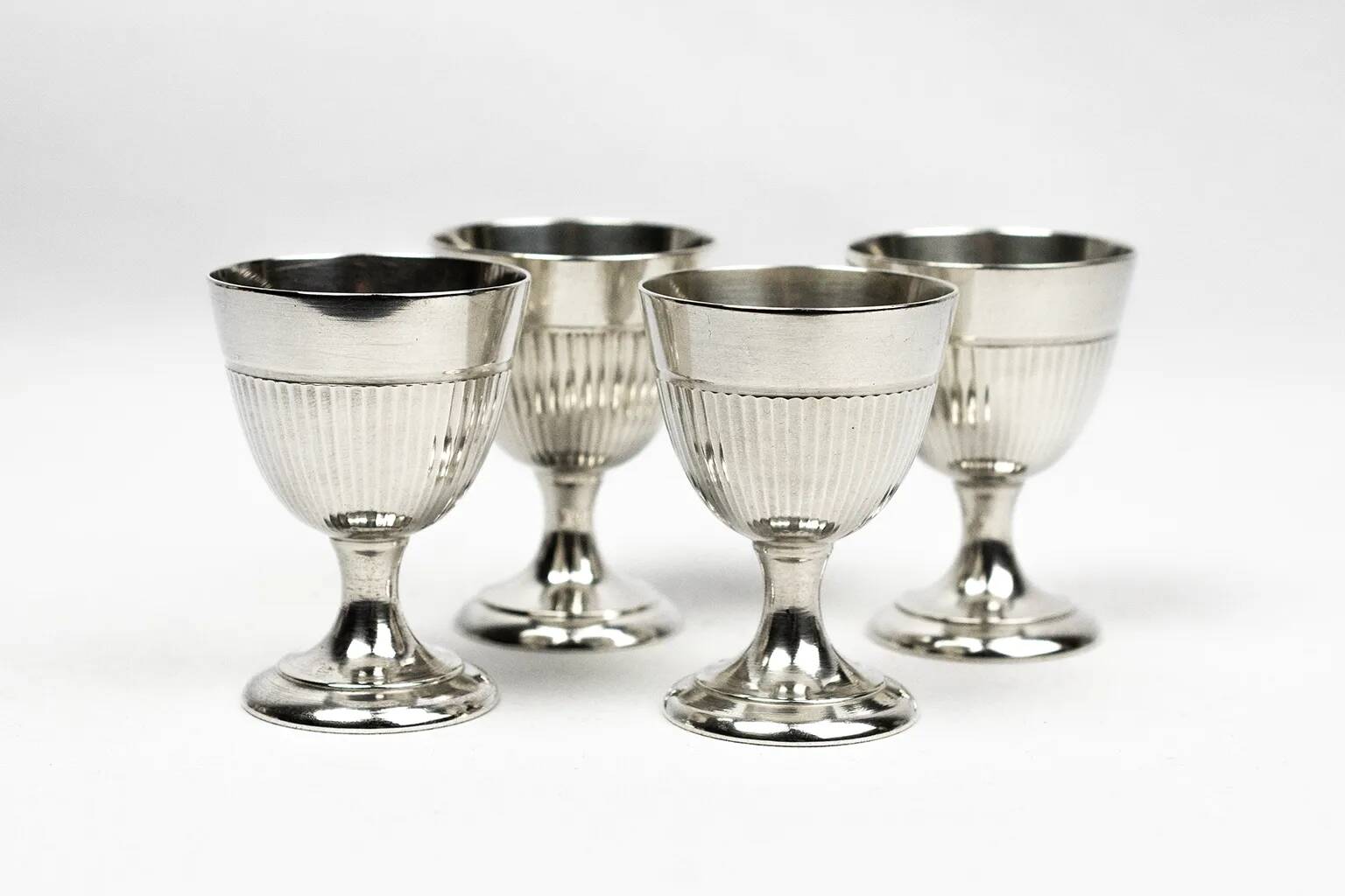Four silver-plated Christofle egg cups with fluted sides.