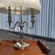 Two-armed hot water bottle lamp in silver metal with fringed fabric shade
