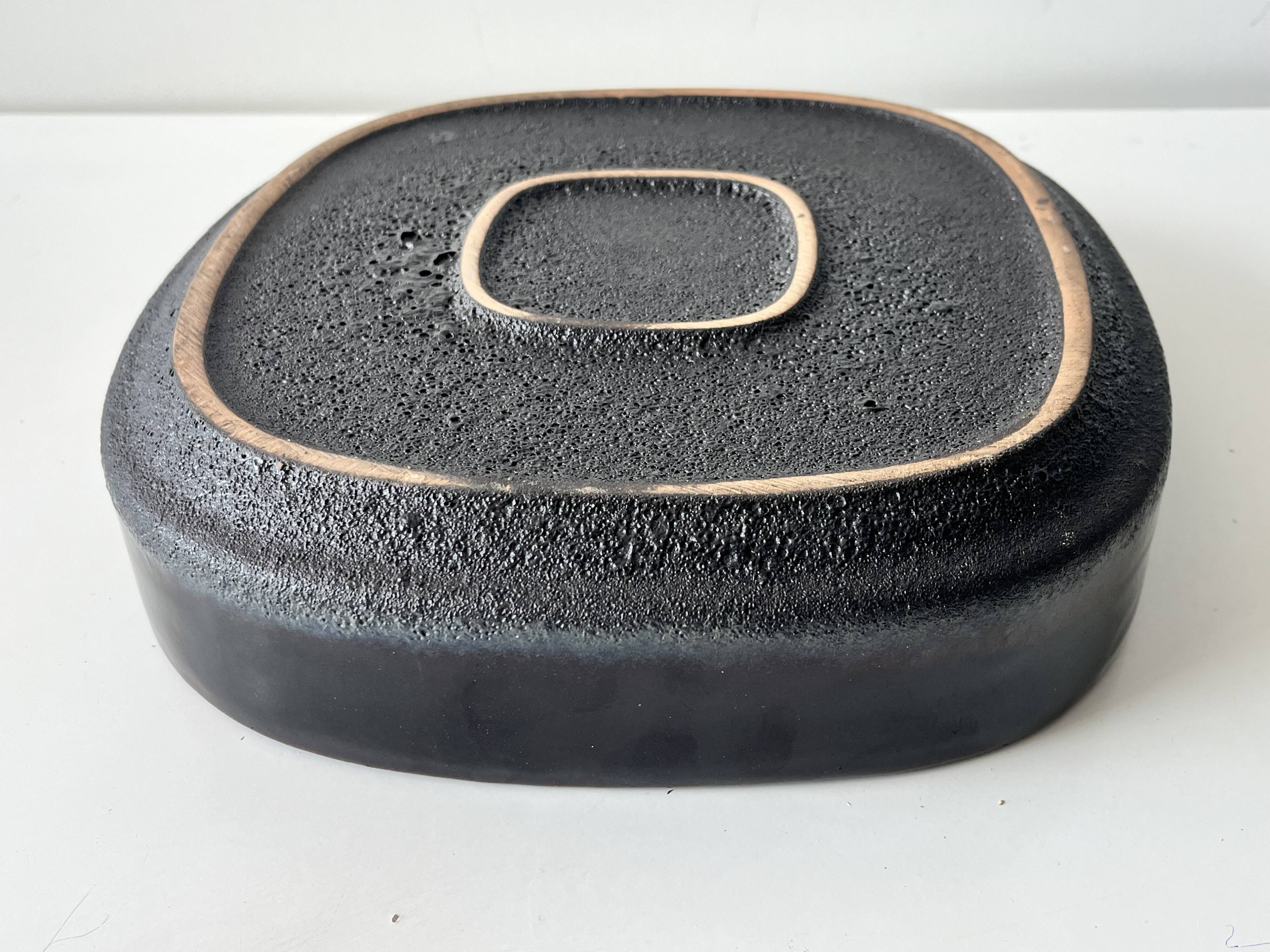 Large decorative ceramic catchall with red and black spiral pattern.