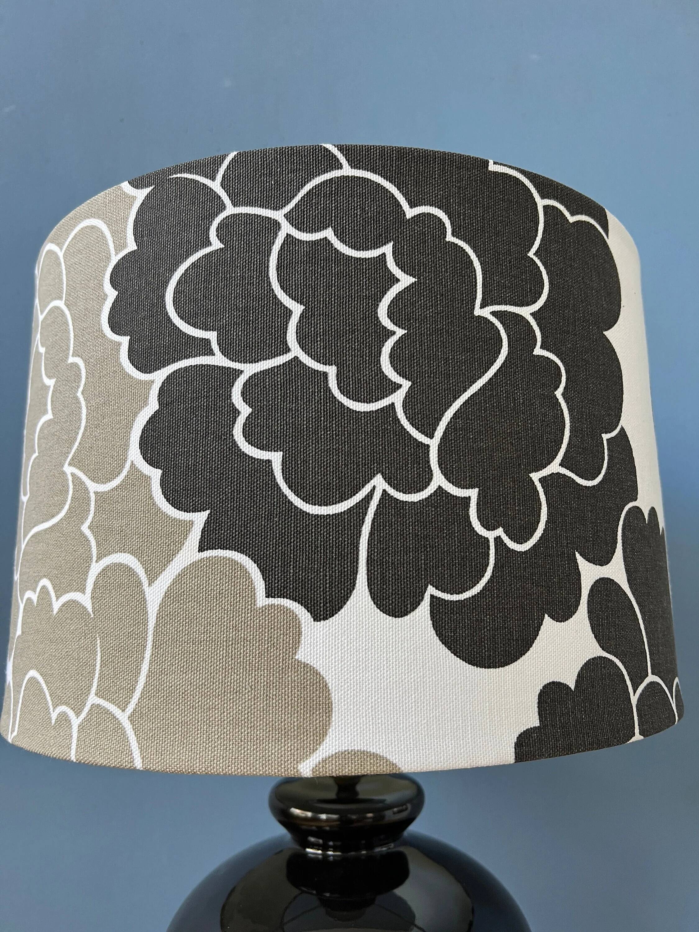 Small Space Age table lamp with a porcelain base and black and white flower shade.