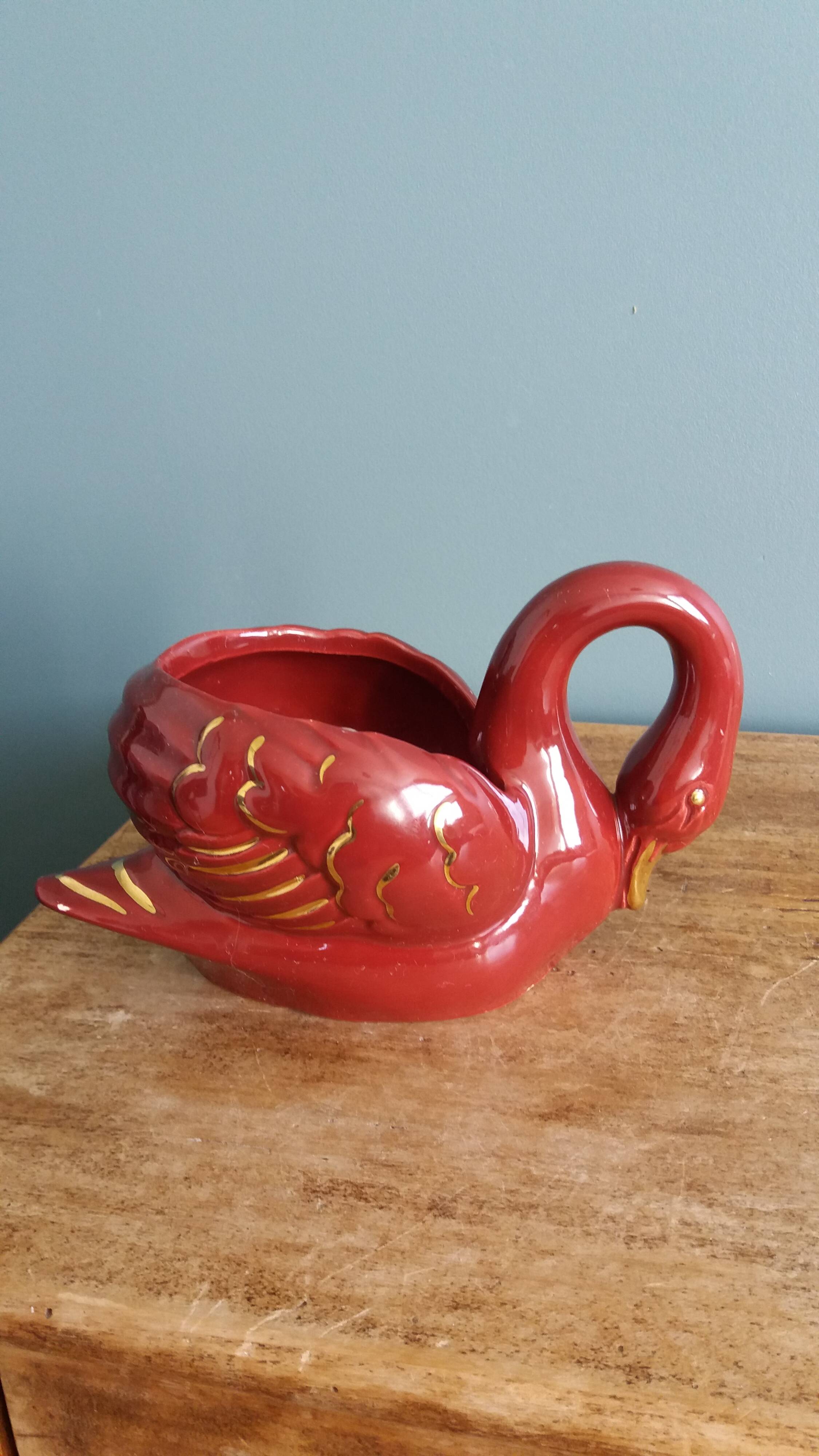 Poet Laval swan hides zoomorphic pot in burgundy ceramic.