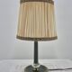 Brass table lamp with green patina and empire-style fabric shade.