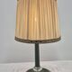 Brass table lamp with green patina and empire-style fabric shade.