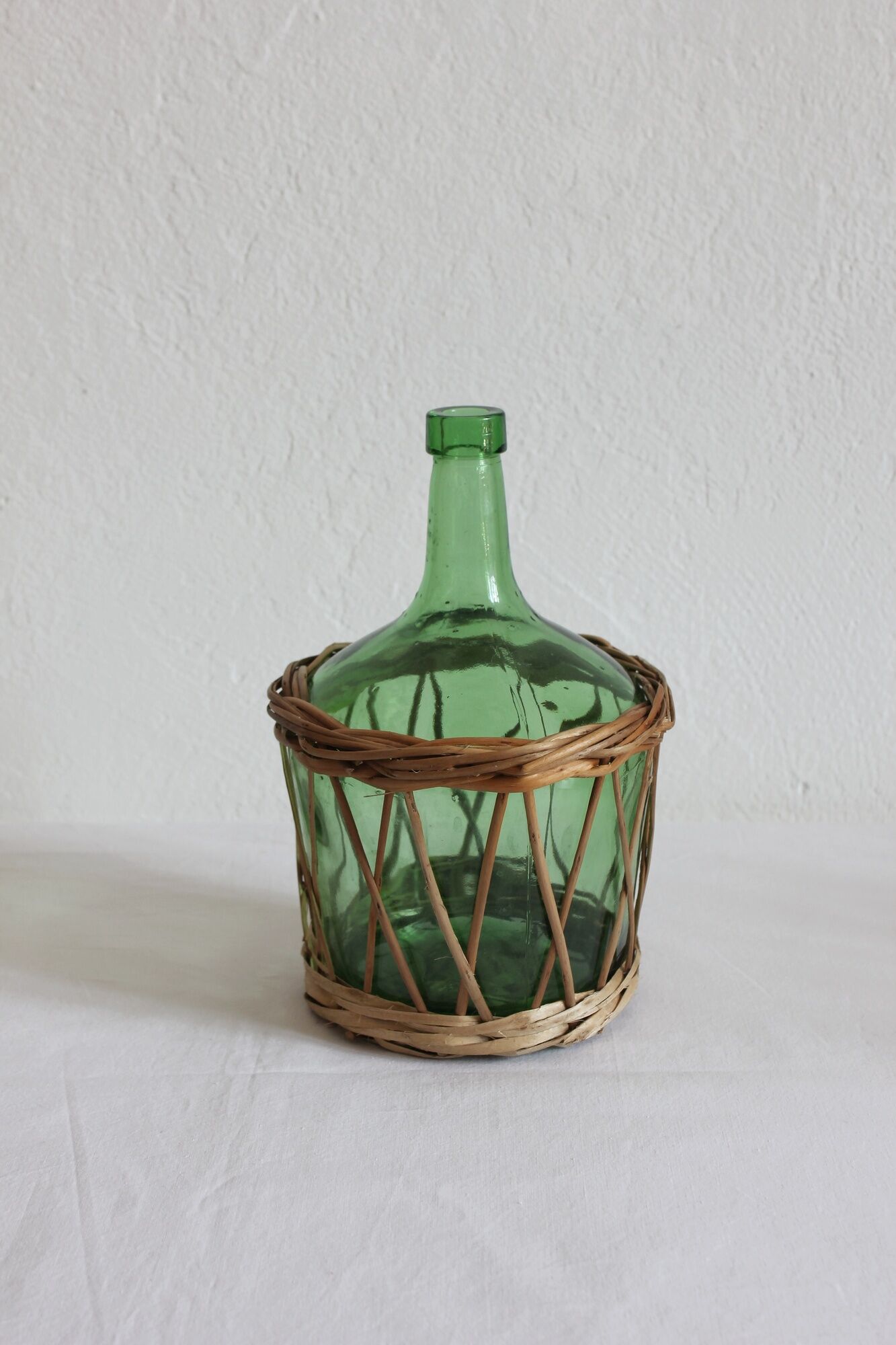 Dame jeanne verte vintage entourée de rotin / osier