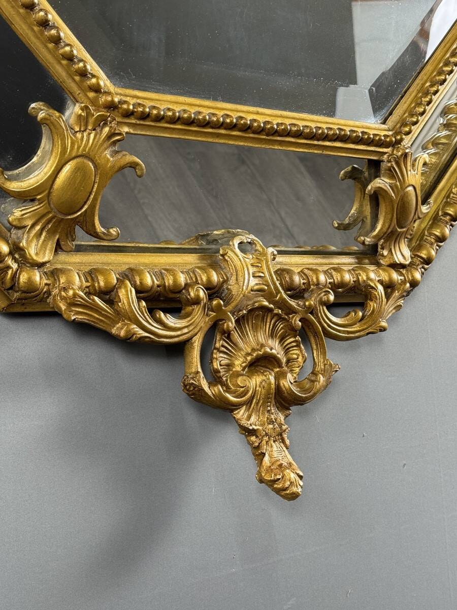 Antique octagonal mirror in richly carved gilded wood, Louis XV style.