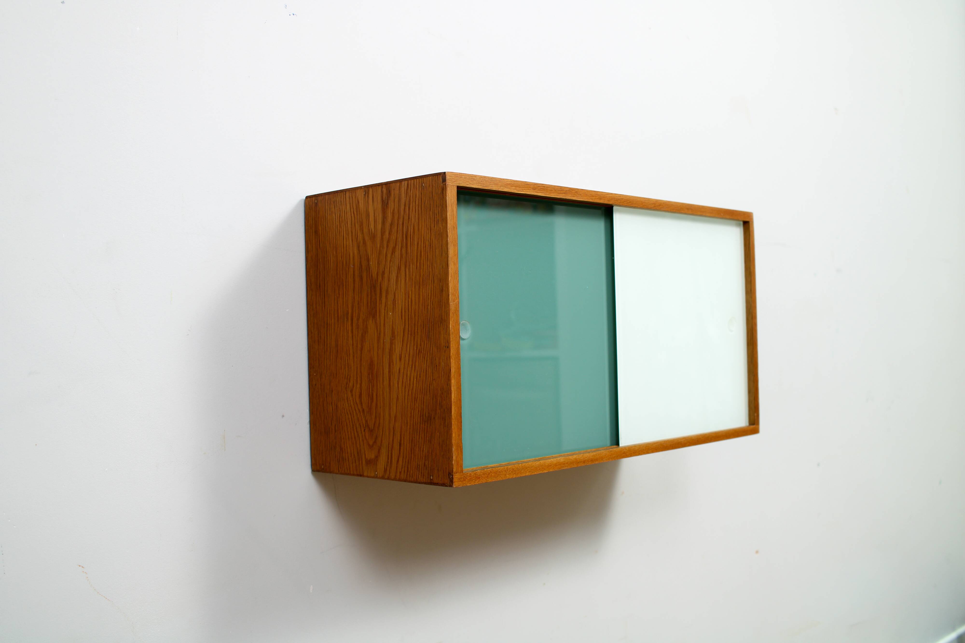 A vintage mid-century wall hung oak cabinet, green & white glass doors