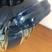 Vase in glazed ceramic decoration drips on blue background