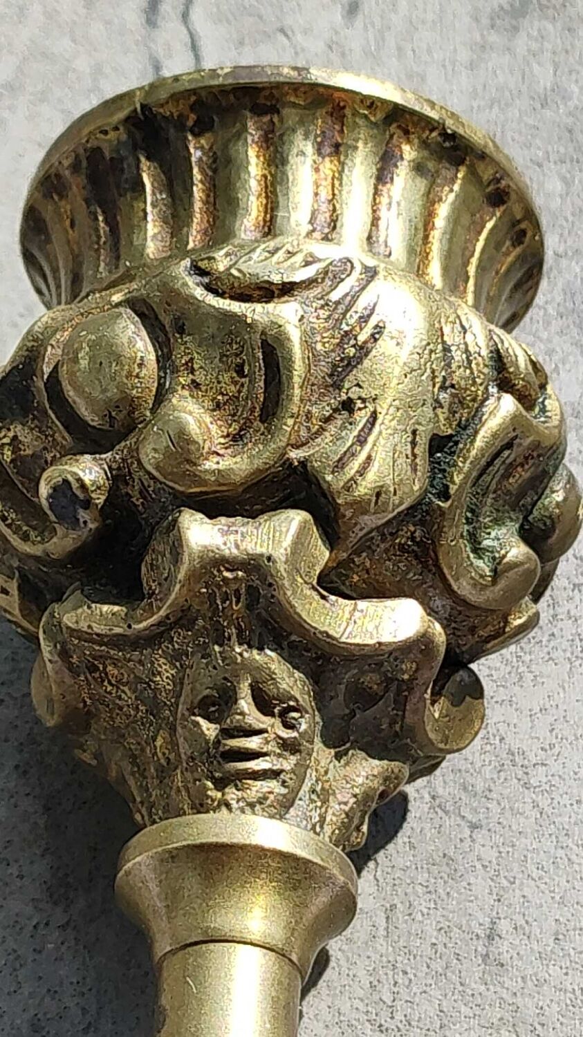 Baroque/Antique style torch candleholder, nineteenth, gilded bronze. Head motifs, volute arabesques