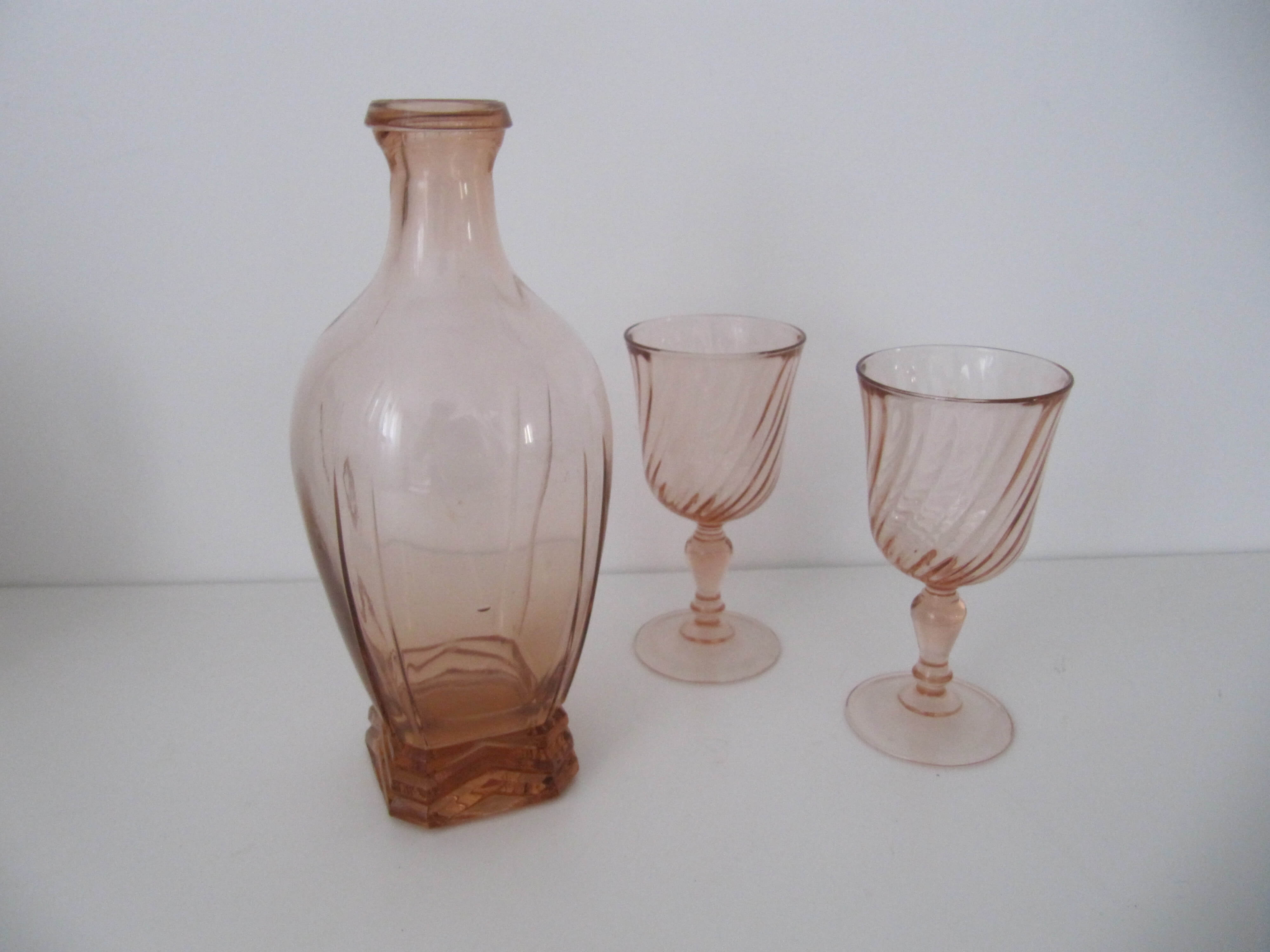 Old bottle in pink glass and 2 wine glasses