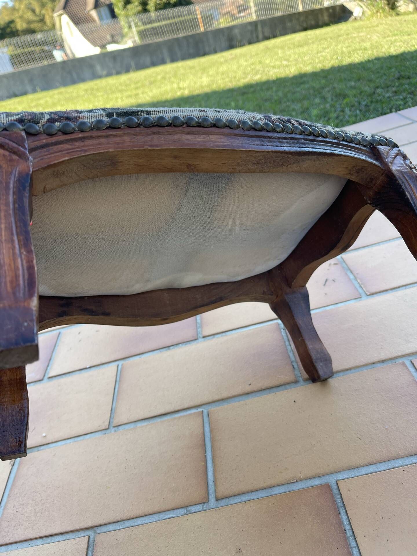 Antique wooden footstool with hand-carved details and floral upholstery –