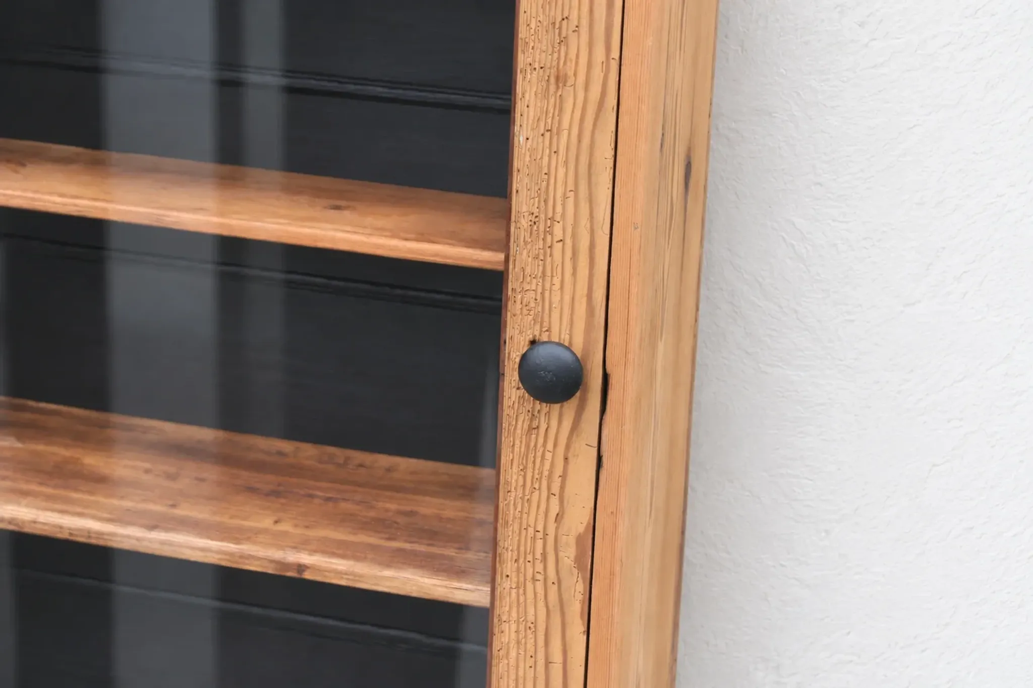 Antique wall display cabinet in natural wood and black – small glass-fronted collector's piece.