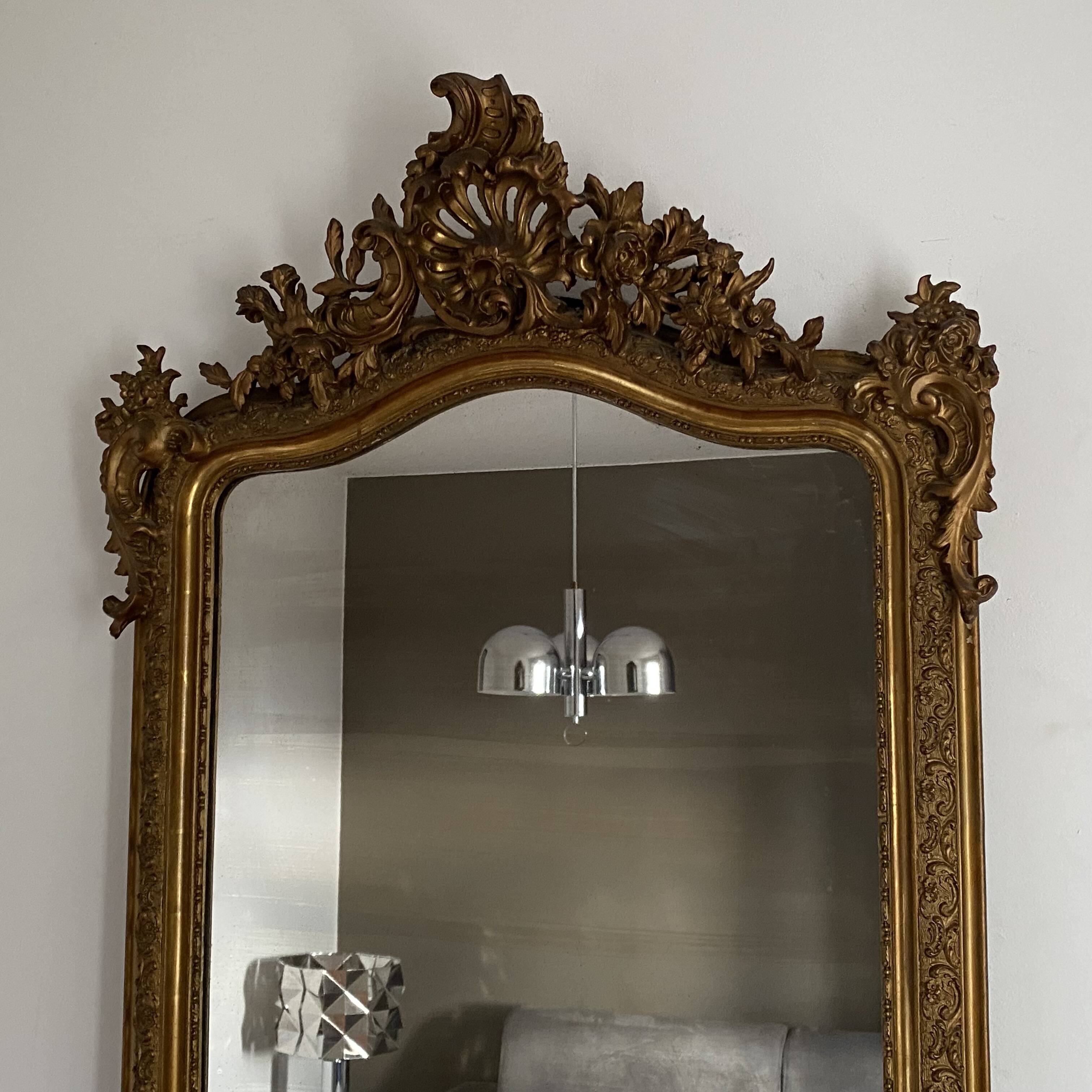 Late 19th century gilded mirror with decorated pediment. 155x88.