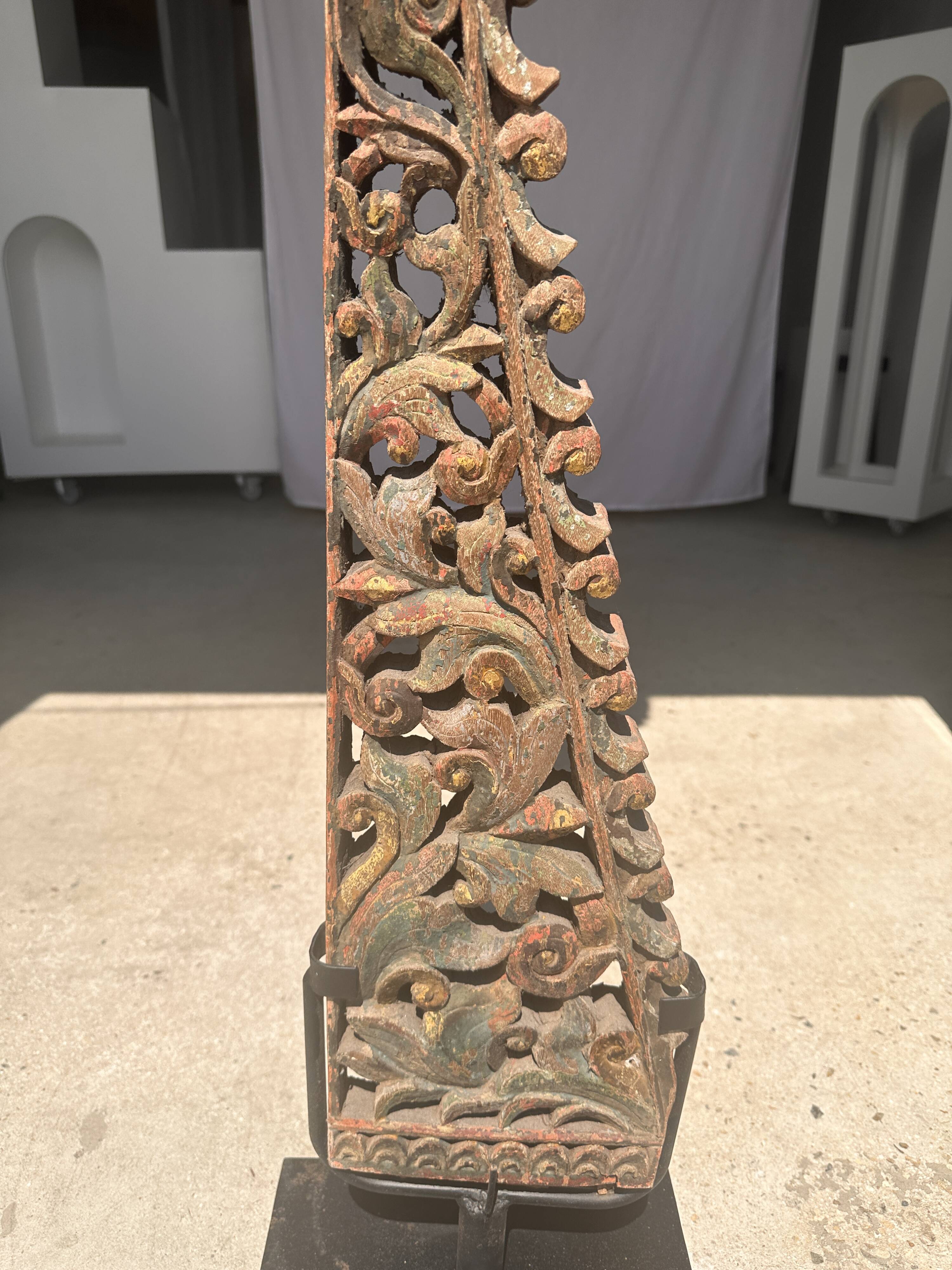 Indonesian construction element in carved wood with intertwined plant motifs mounted on a base (fri
