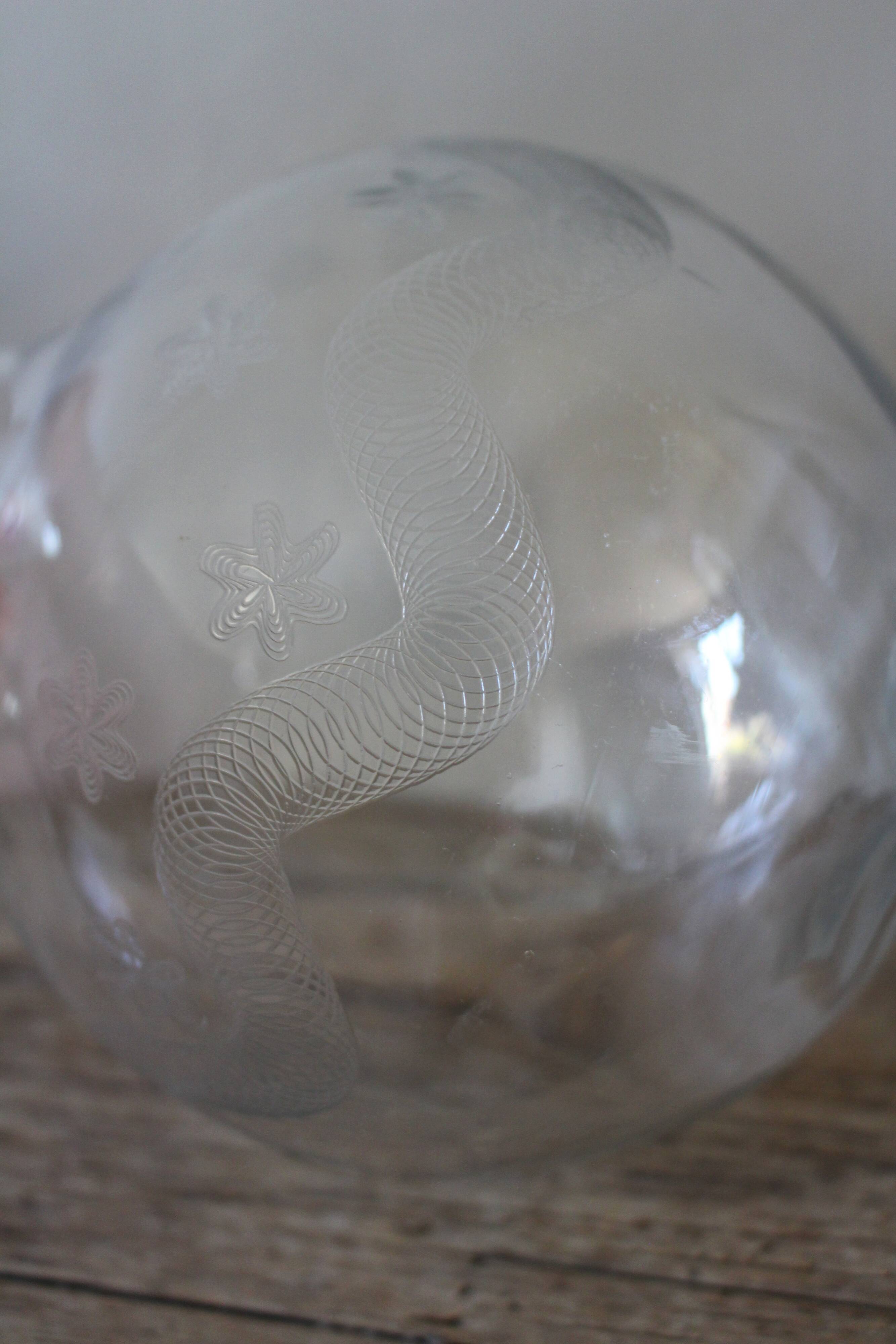 Antique glass carafe with a round belly and floral neck.