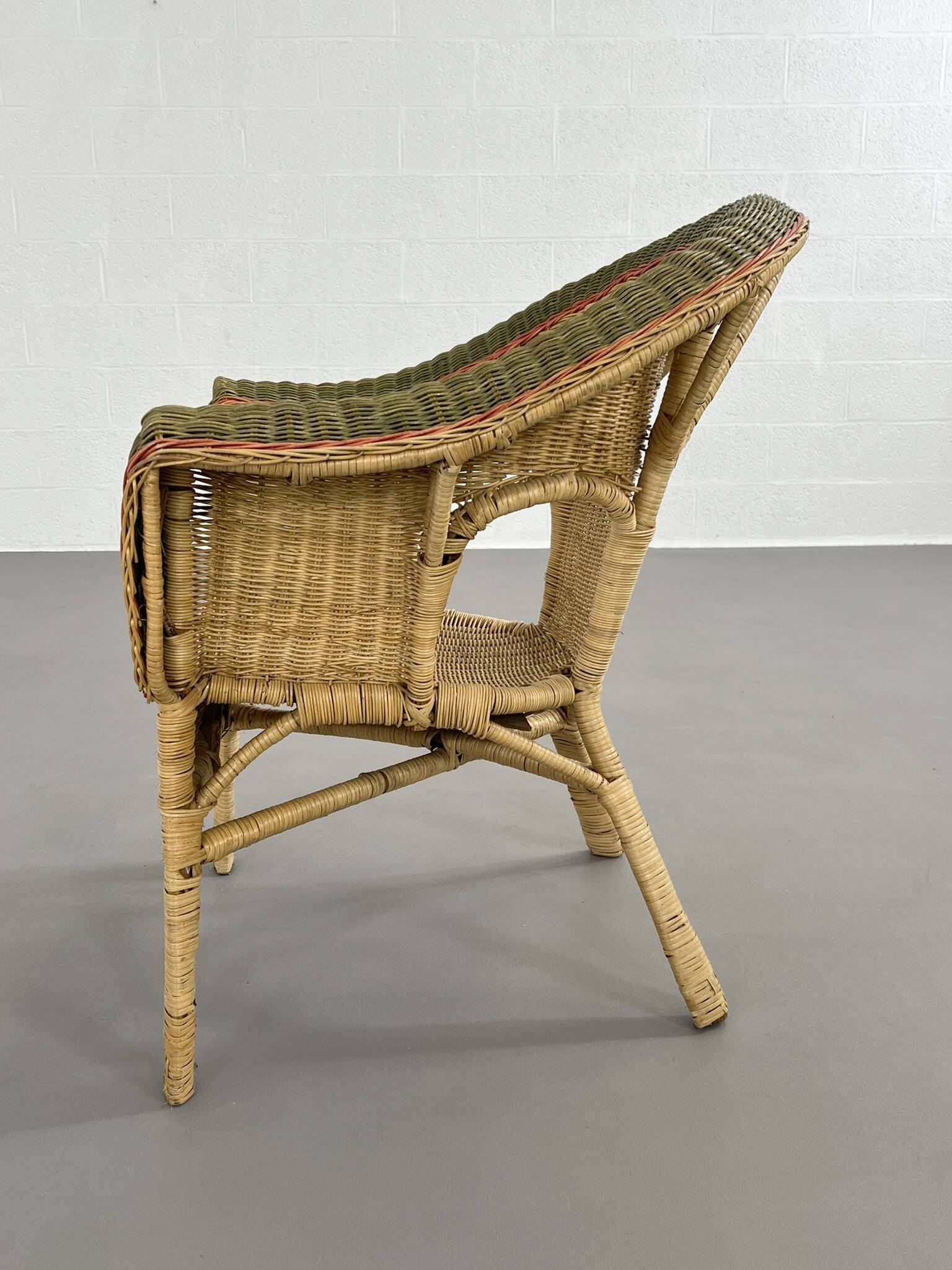 Cabriolet style armchair in rattan, wicker and green and red edging