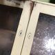 Vintage wooden kitchen cupboard painted green and beige, with glass doors - 1930s