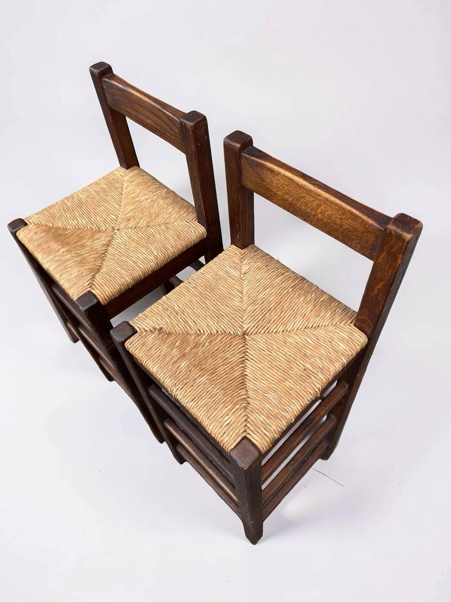 Set of 2 vintage wooden bar stools with woven straw seats.