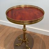 A round, neoclassical-style brass side table with a base decorated with dolphins and a red celluloid top encircled by an openwork gallery, attributed to the House of Jansen.
