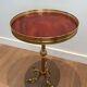 Guéridon rond de style néoclassique en laiton à piètement décoré de dauphins et plateau de celluloïde rouge cerclé d'une gallerie ajourée attribué à la Maison Jansen