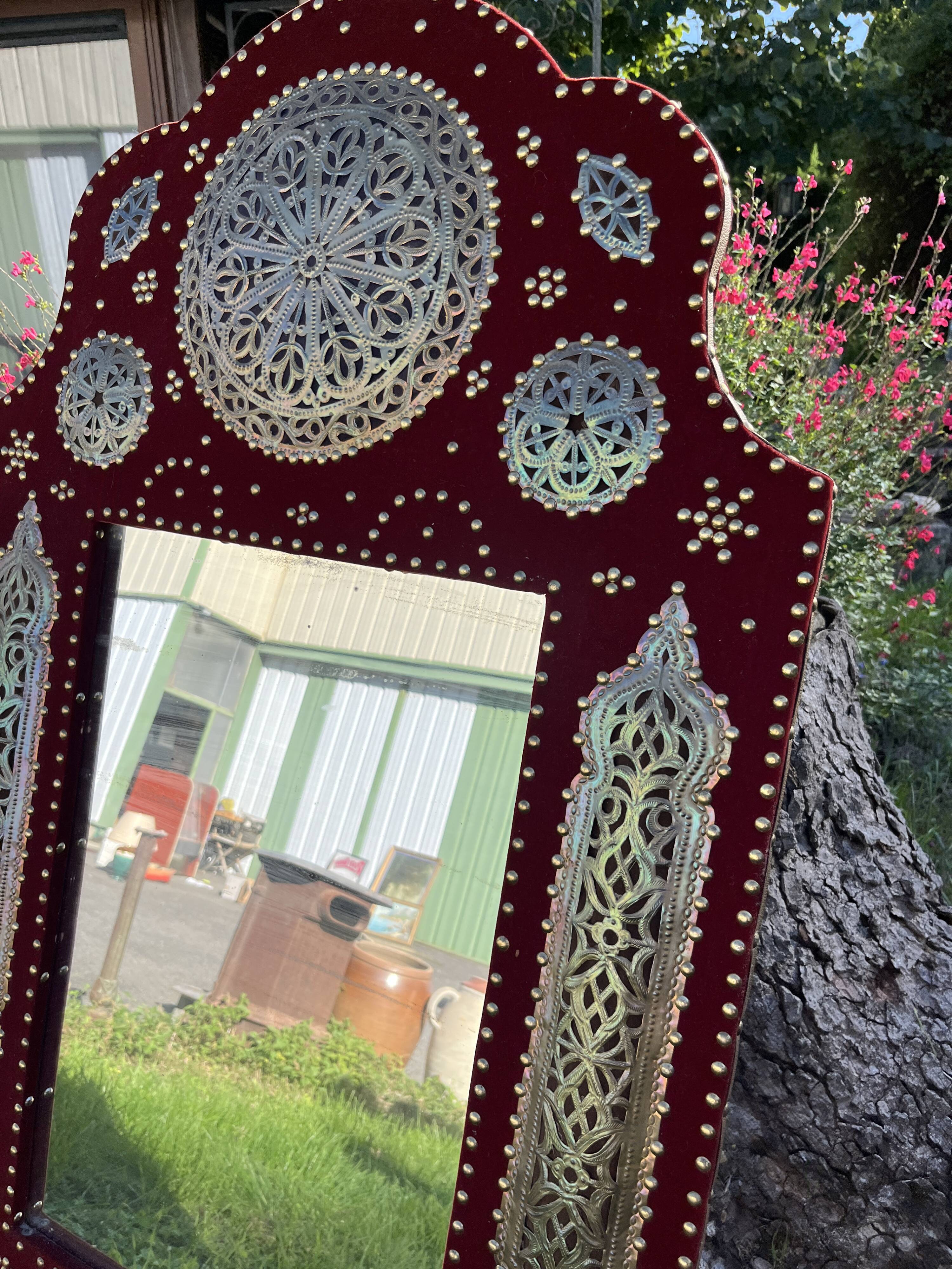 Large oriental mirror with embossed brass decoration on a red velvet background