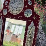 Large oriental mirror with embossed brass decoration on a red velvet background