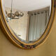 Oval wooden frame with floral decoration in gold.