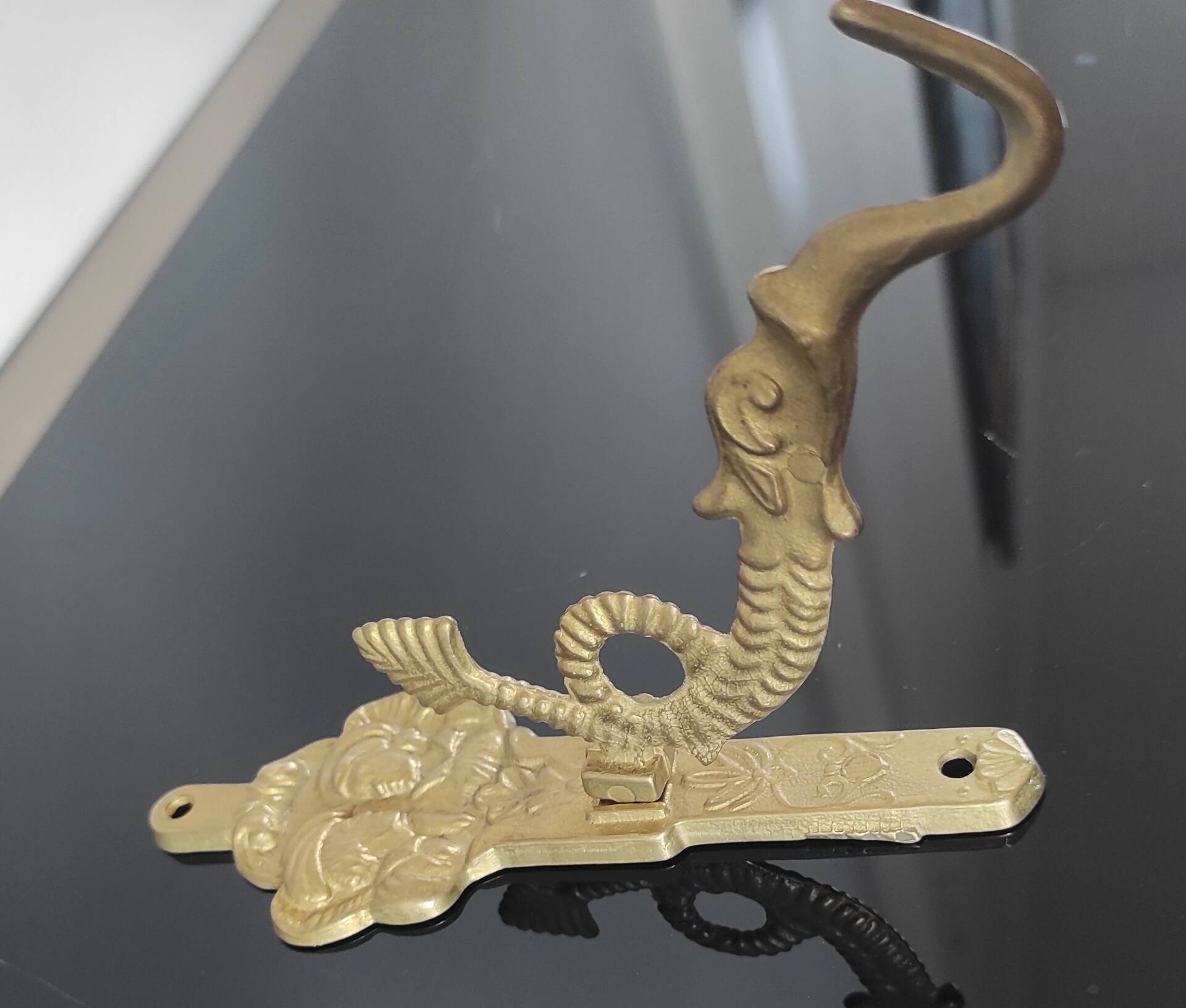 Vintage brass coat hook with marine creature motif and medallion.