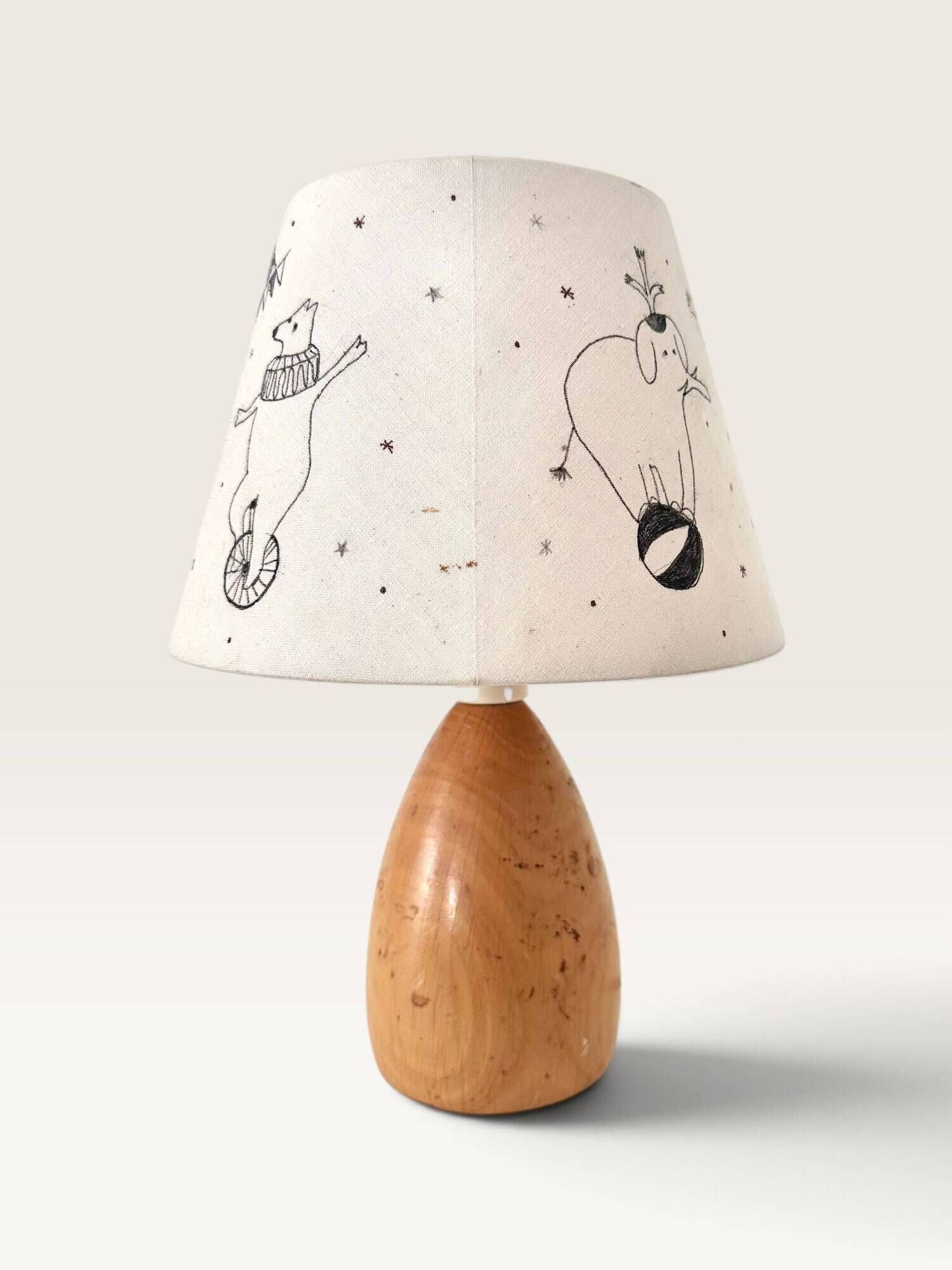Wood-turned lamp with a hand-drawn lampshade, circus patterns.