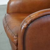 Cognac-colored sheepskin armchair with rounded shapes