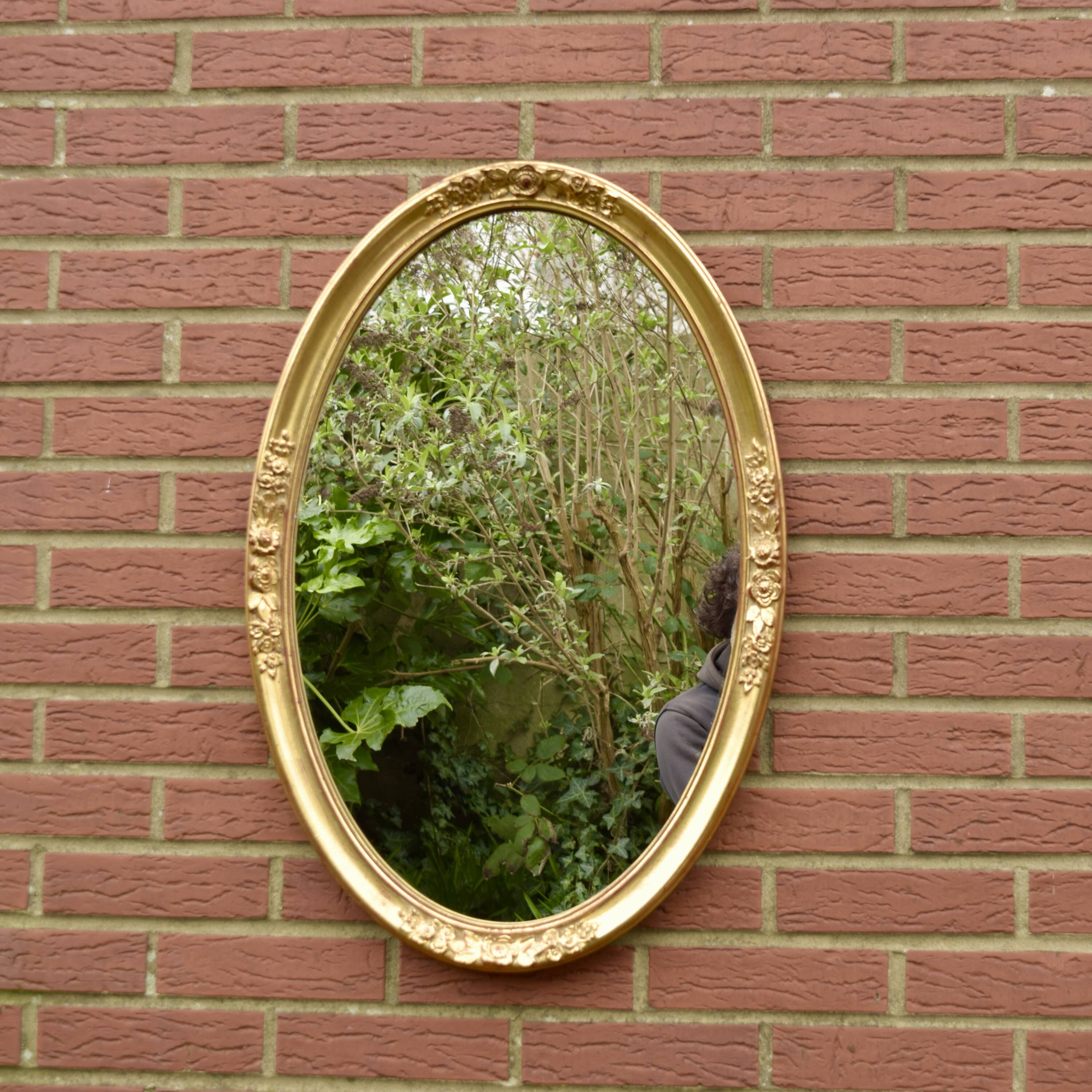Old large oval wall mirror in golden resin