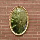 Old large oval wall mirror in golden resin