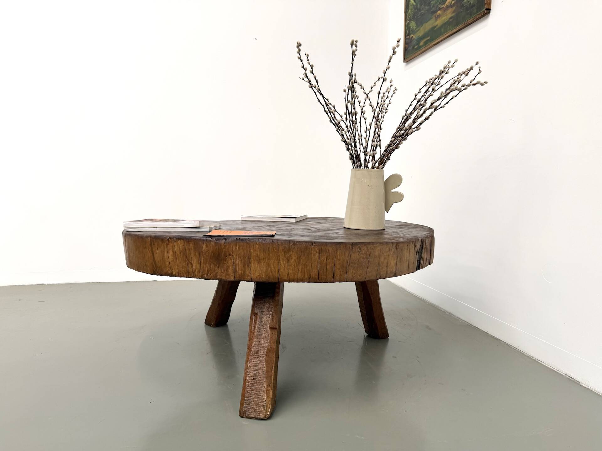 Brutalist coffee table in solid teak, monolithic slab, tripod base.