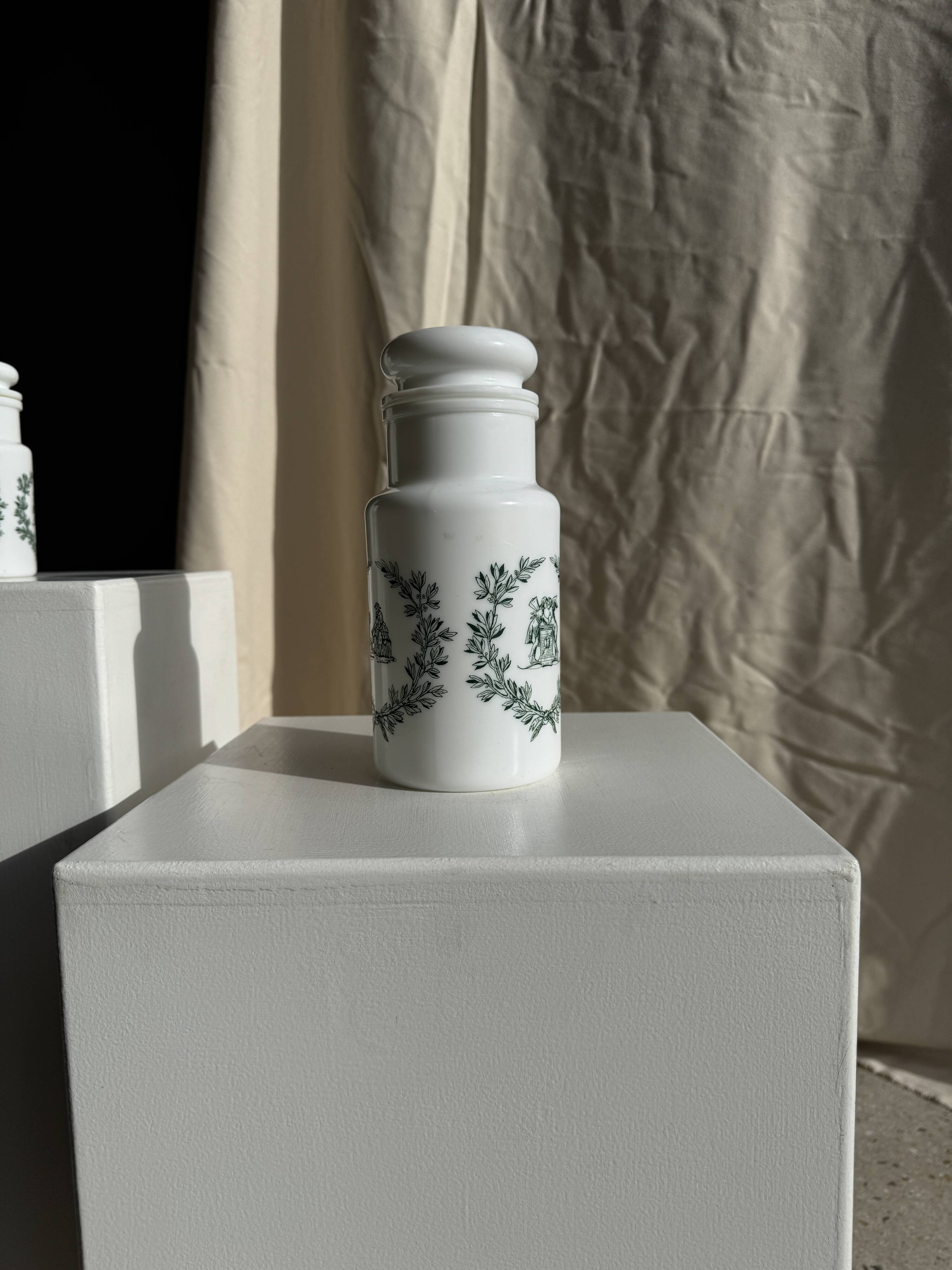 A pair of white glass bottles with Italian green patterns.