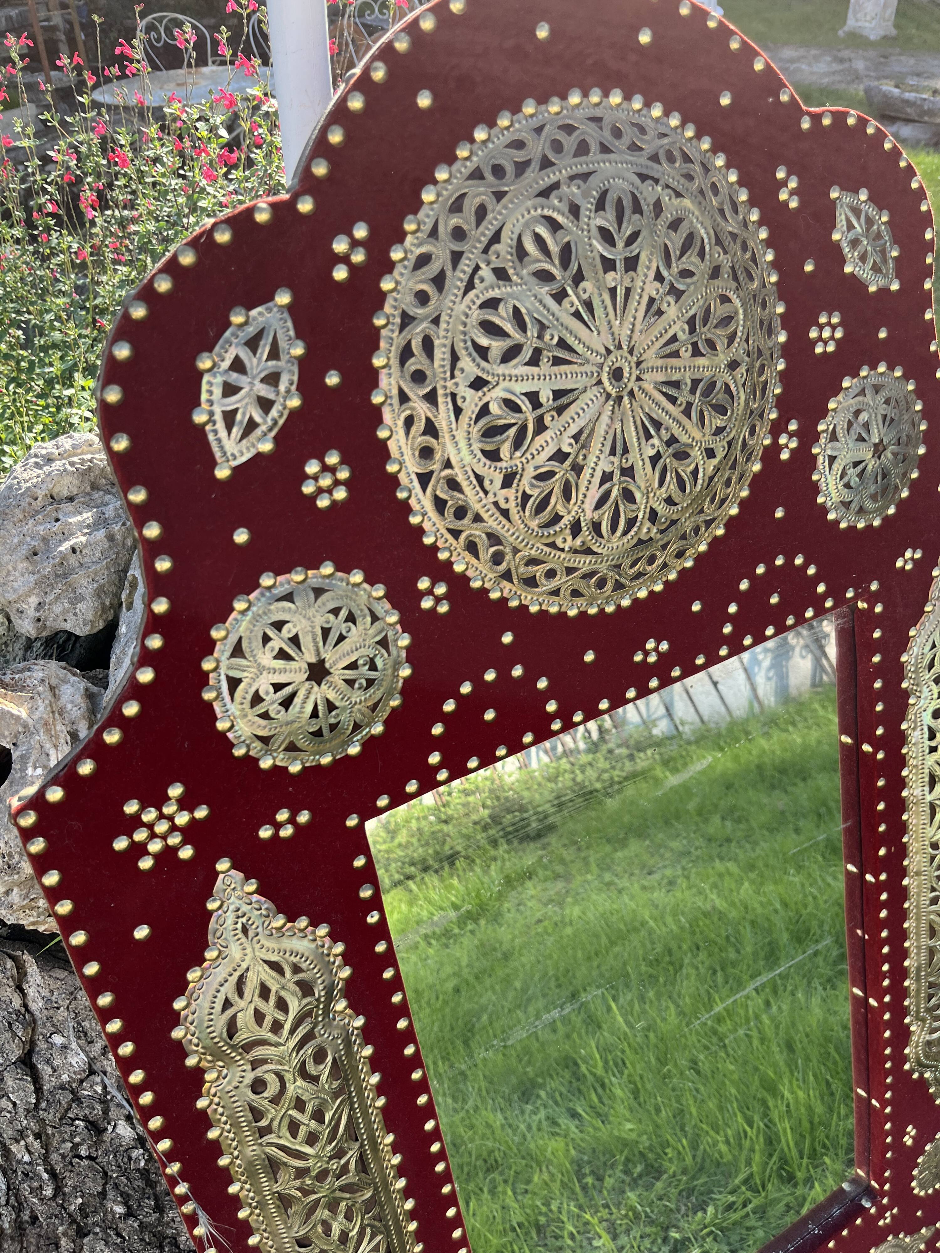 Large oriental mirror with embossed brass decoration on a red velvet background