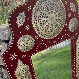 Large oriental mirror with embossed brass decoration on a red velvet background