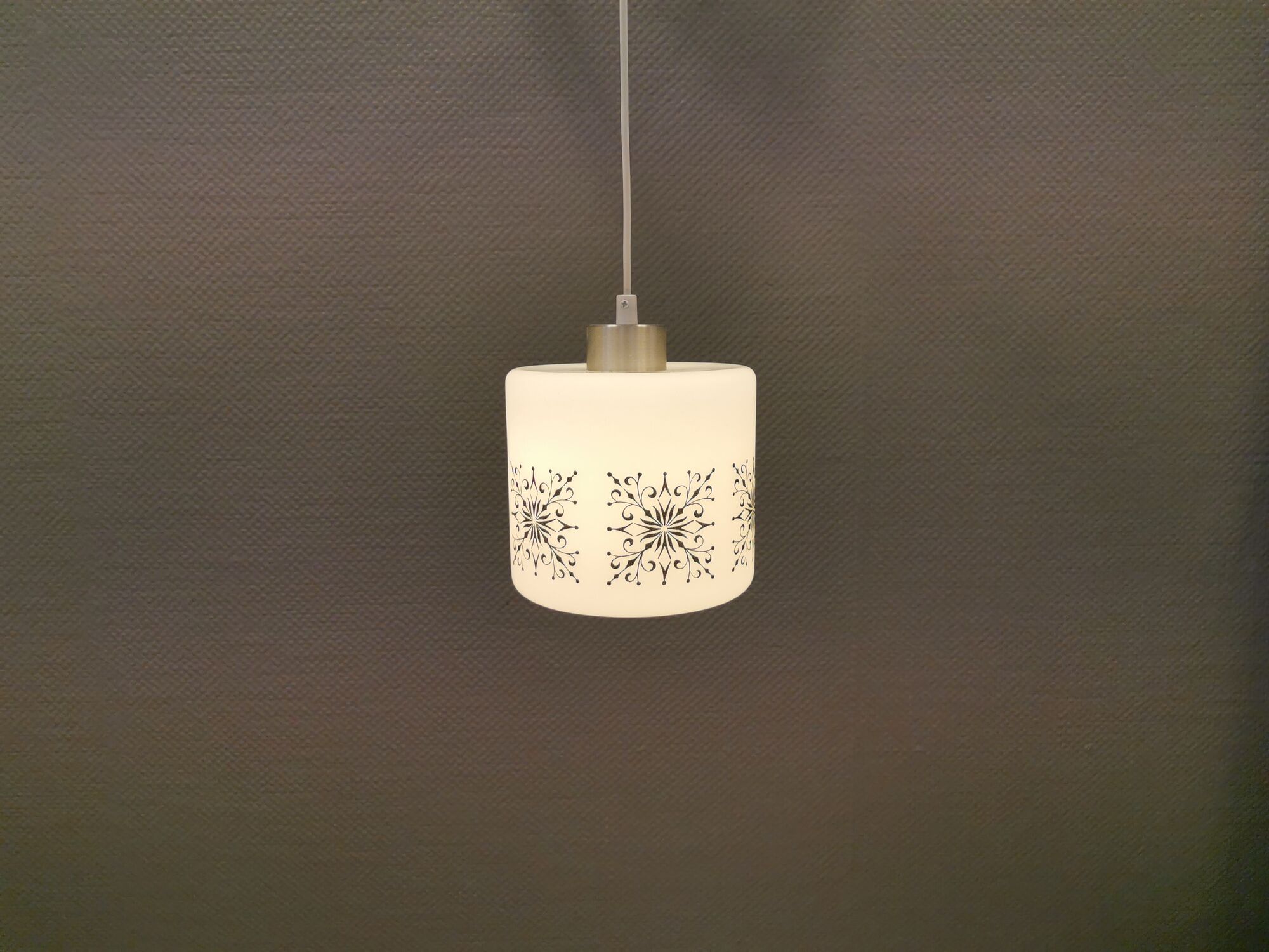 Scandinavian hanging lamp in white glass with inlayed black motifs.