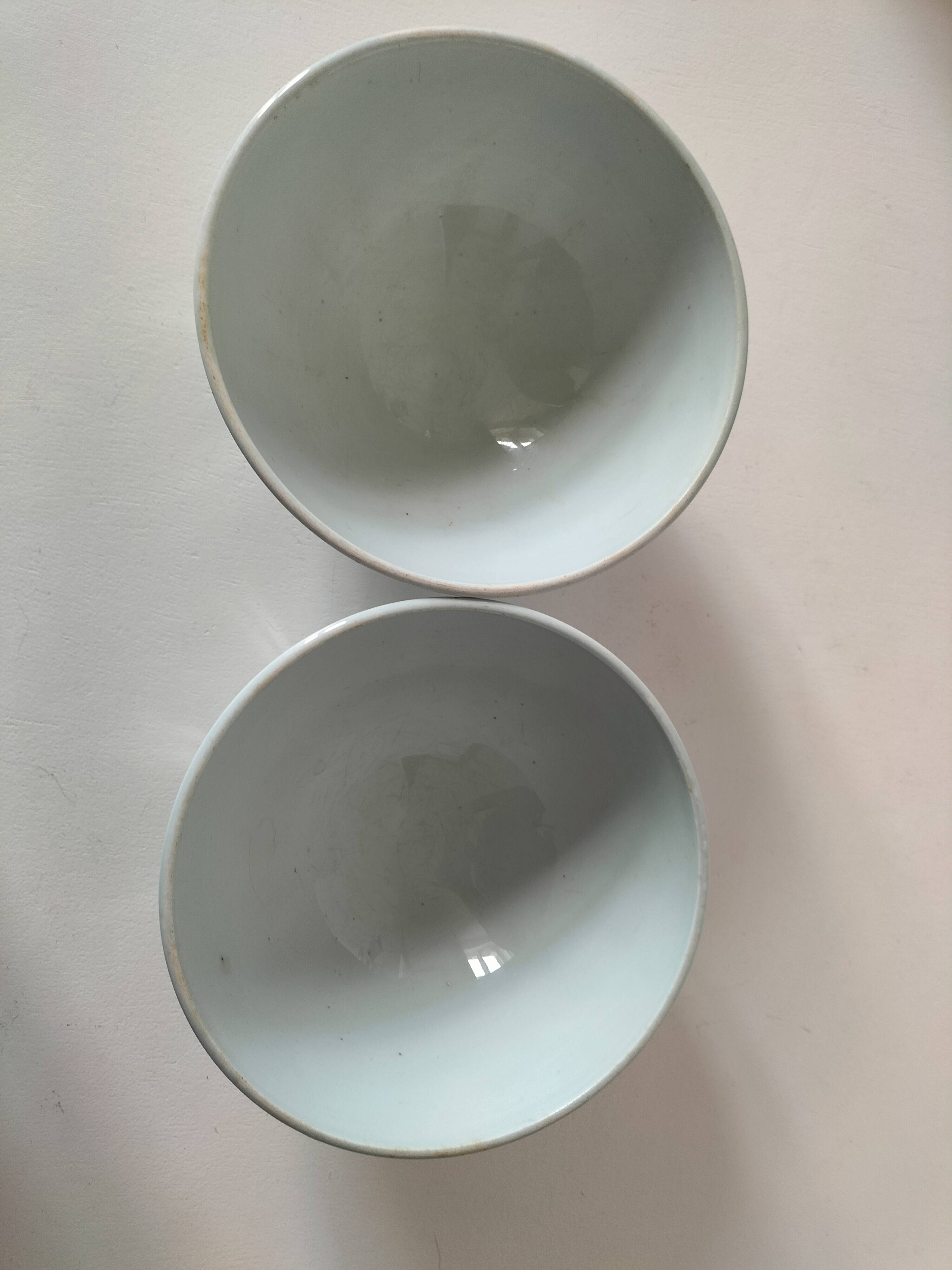 Two vintage farm bowls on a pale blue pedestal with floral decoration.
