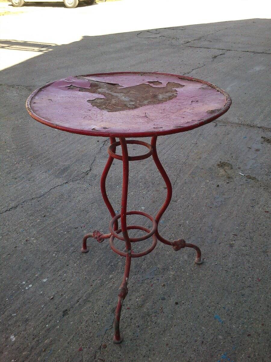 Vintage red cast iron bistro table (1950s) — round metal top, tripod base.