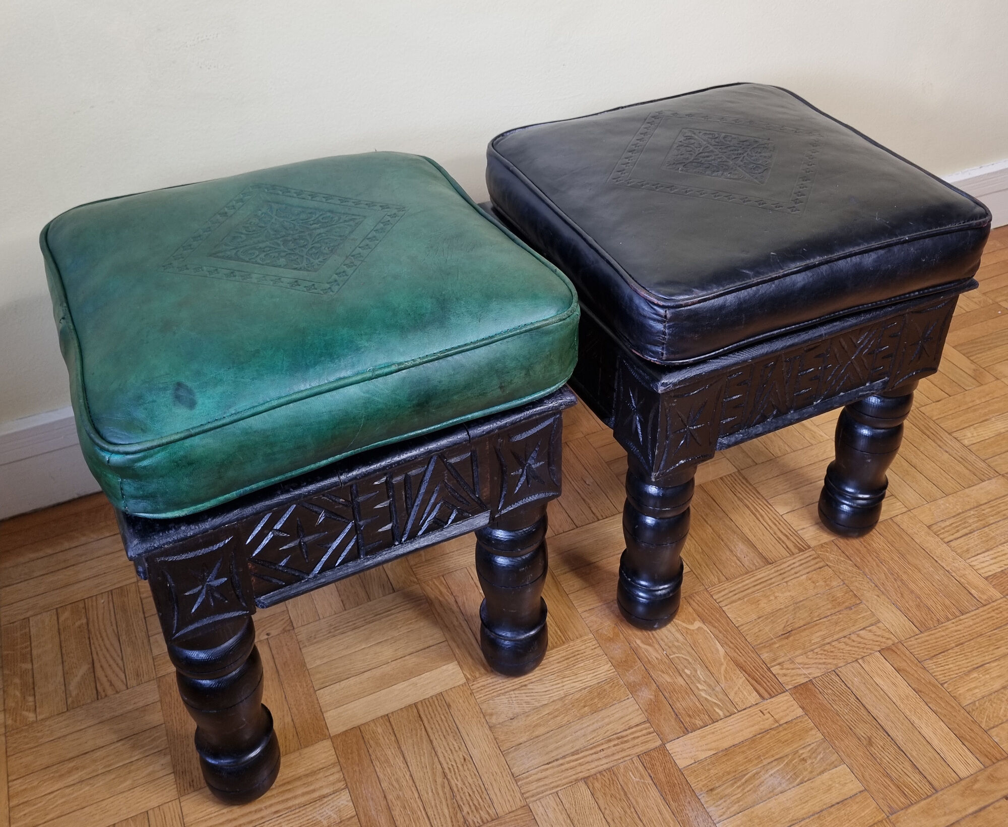 Pair of Moroccan poufs in stamped leather with a carved wooden base, Rabat