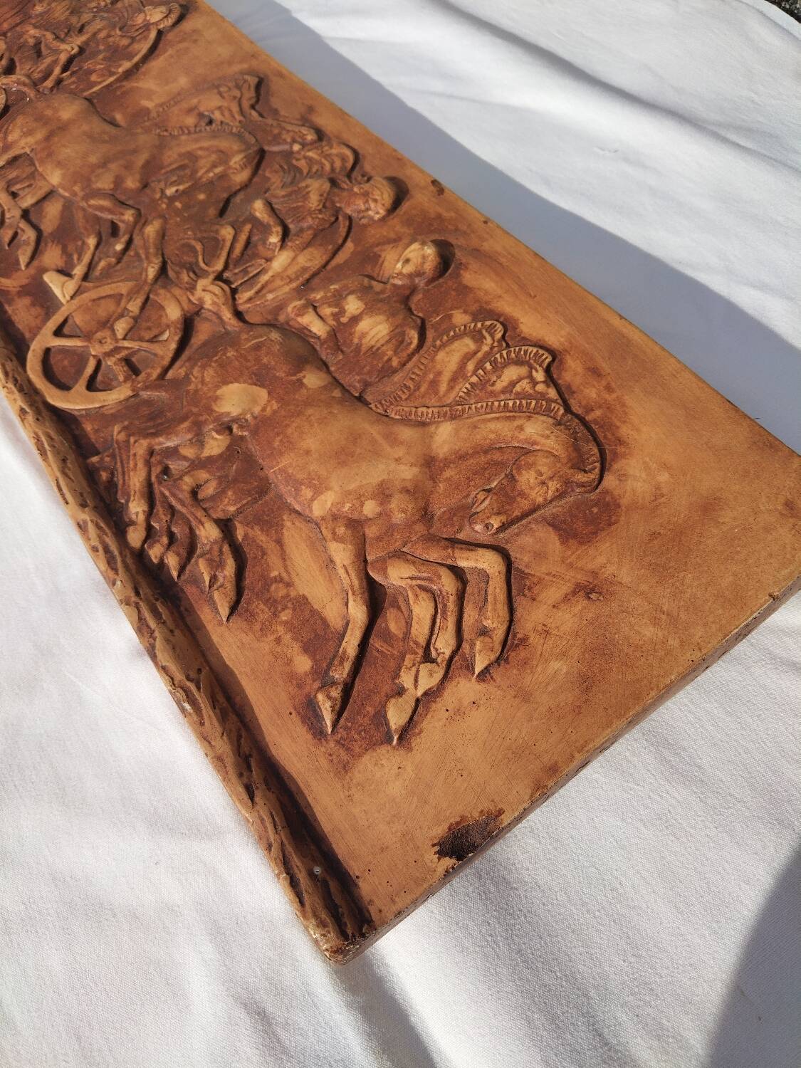 Bas-relief plaster scene of horses and a cart.